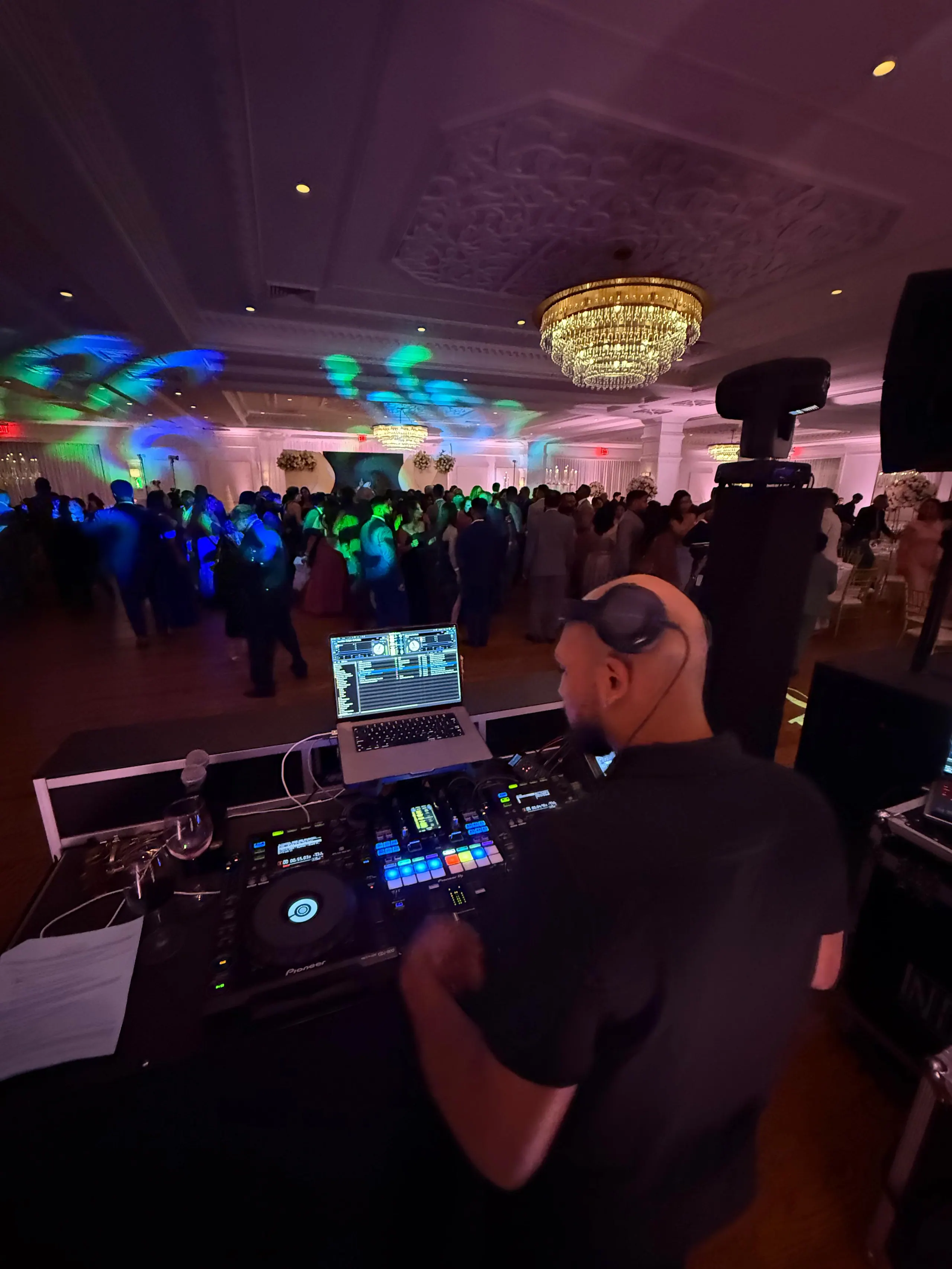 The view from behind the booth across a packed ballroom floor, chandelier overhead
