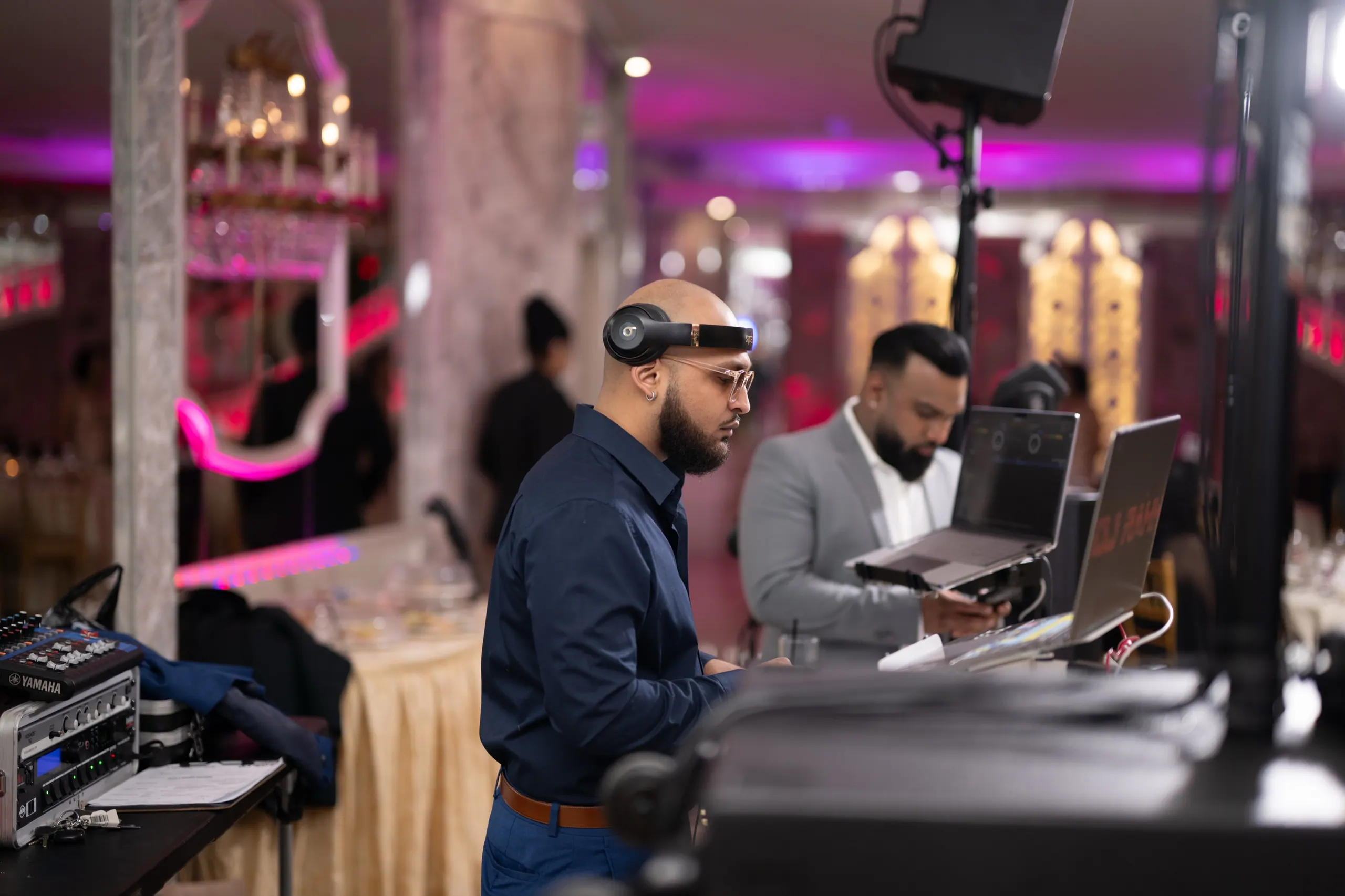 RAHH cueing a track on headphones behind the booth at a banquet hall