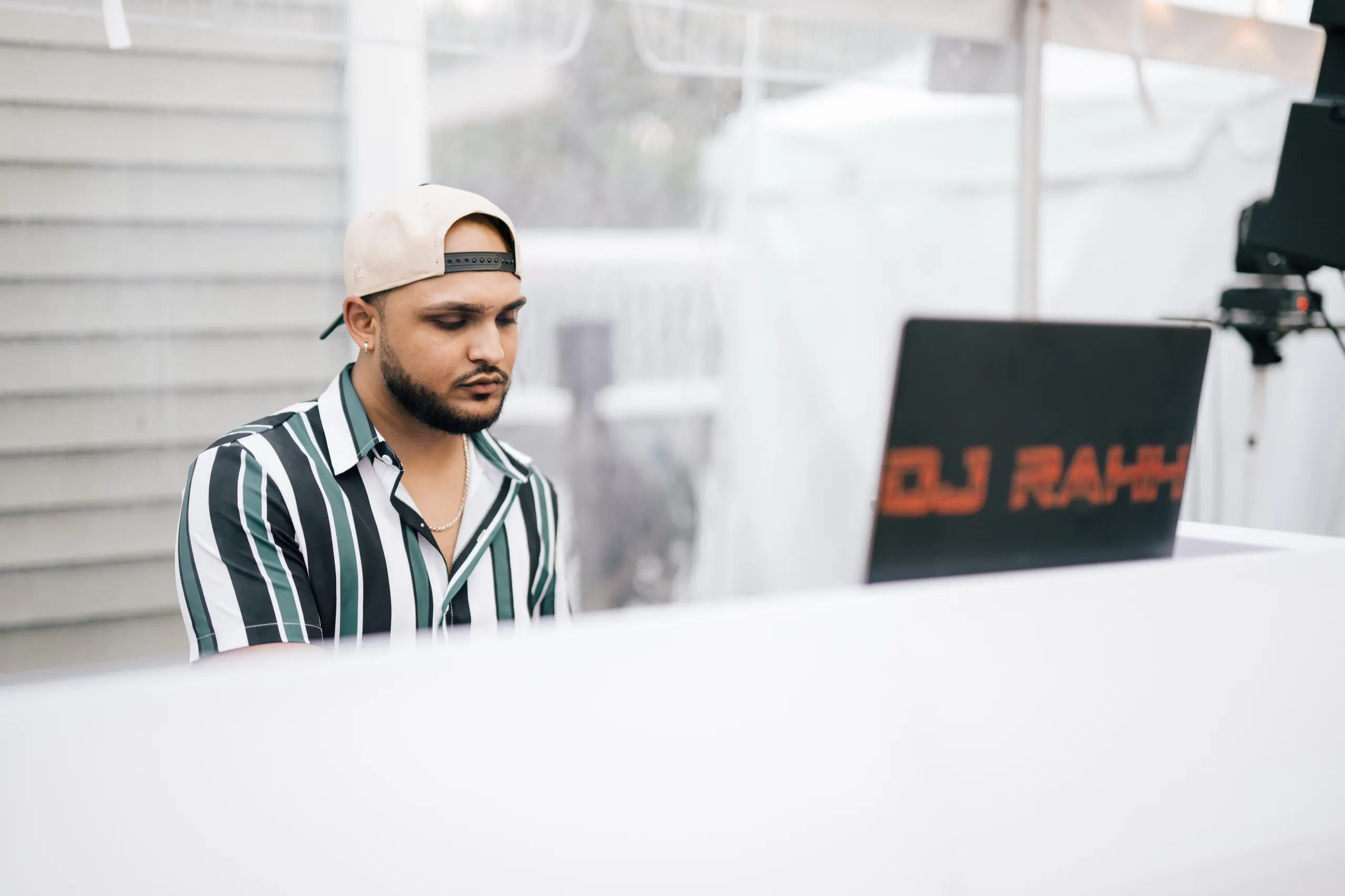 Playing an outdoor set under a marquee, DJ RAHH laptop panel in frame