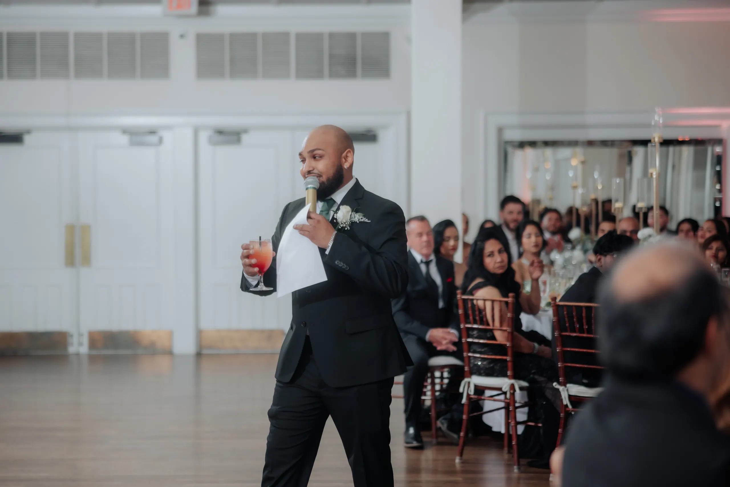 Working the microphone across a reception room, long guest tables to the right