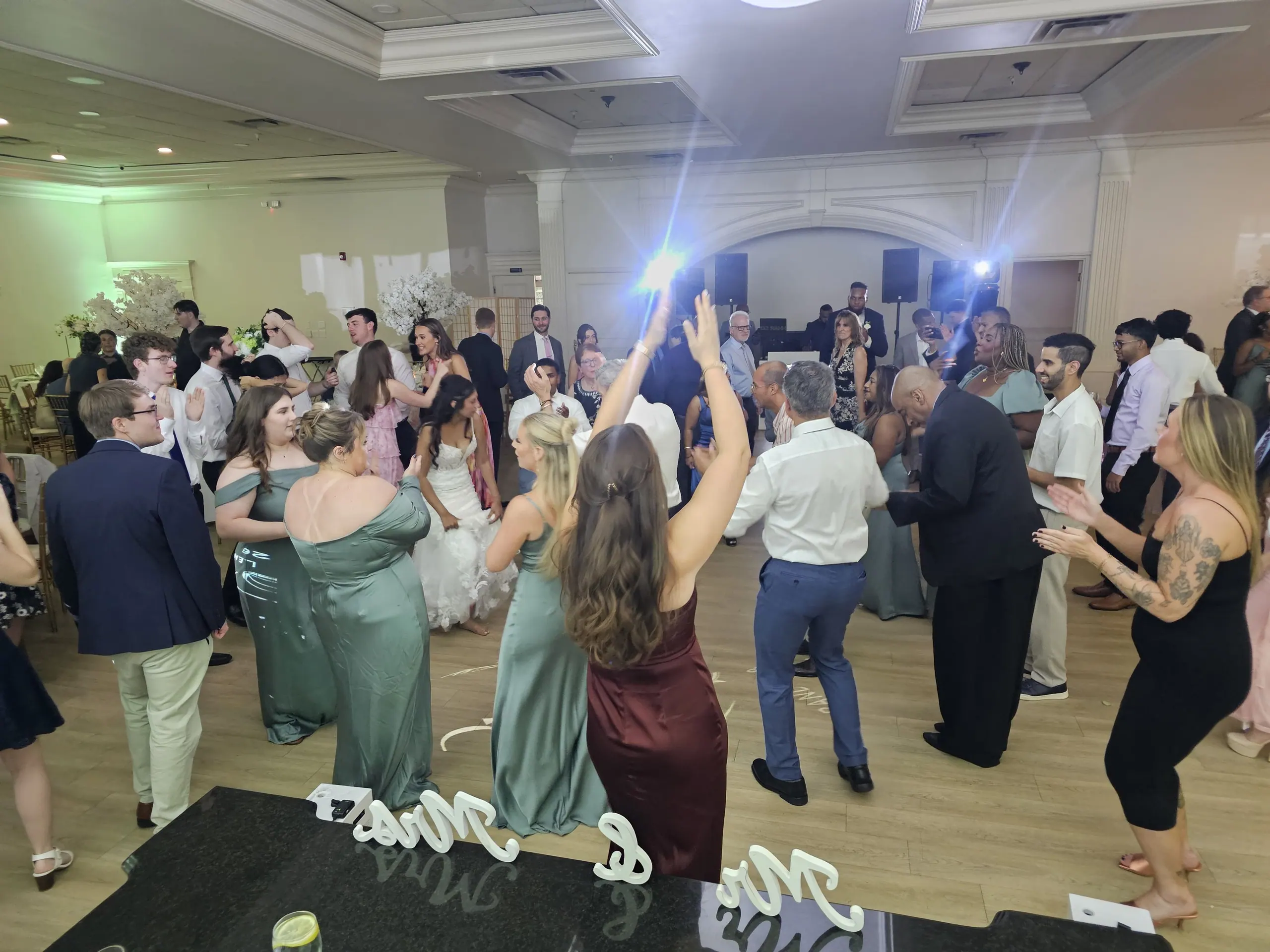 Wedding guests dancing with their hands up, the bride in the middle of the floor